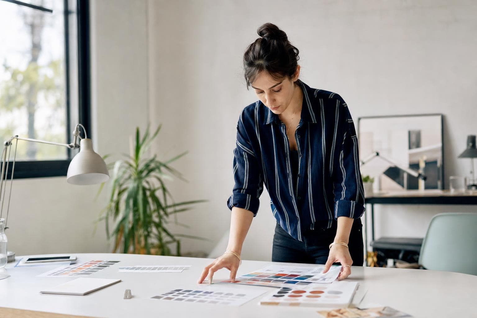 A photo of a designer laying out color swatches and type samples on a bright studio desk.