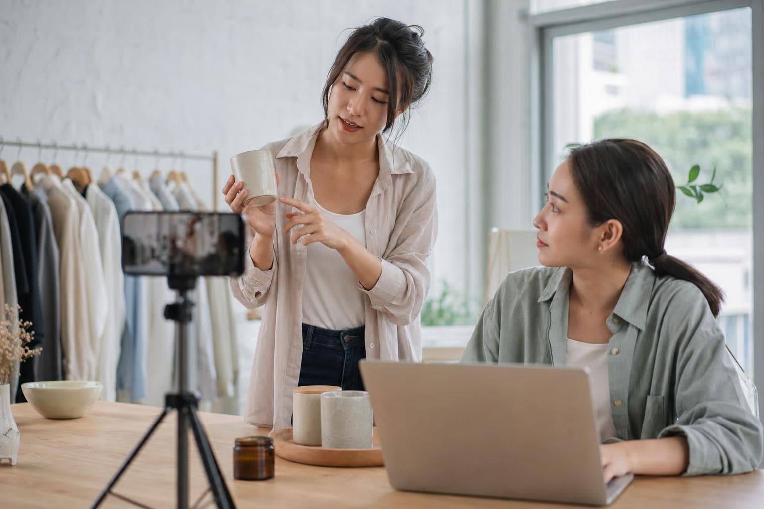 A photo of a business owner recording a simple how-to while a team member follows along on a laptop.