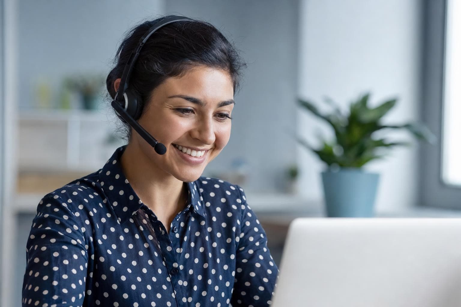 A support-team owner on a headset helping a customer warmly while a screen shows an AI assistant draft.