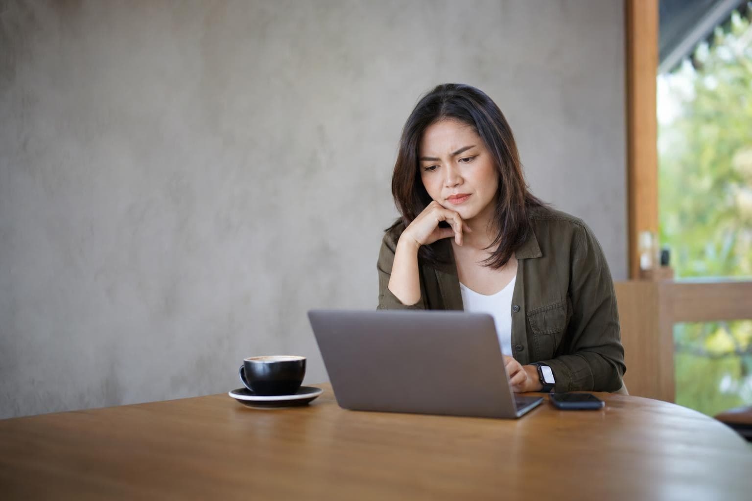 An owner frowning slightly at website analytics on a laptop in a quiet café corner.