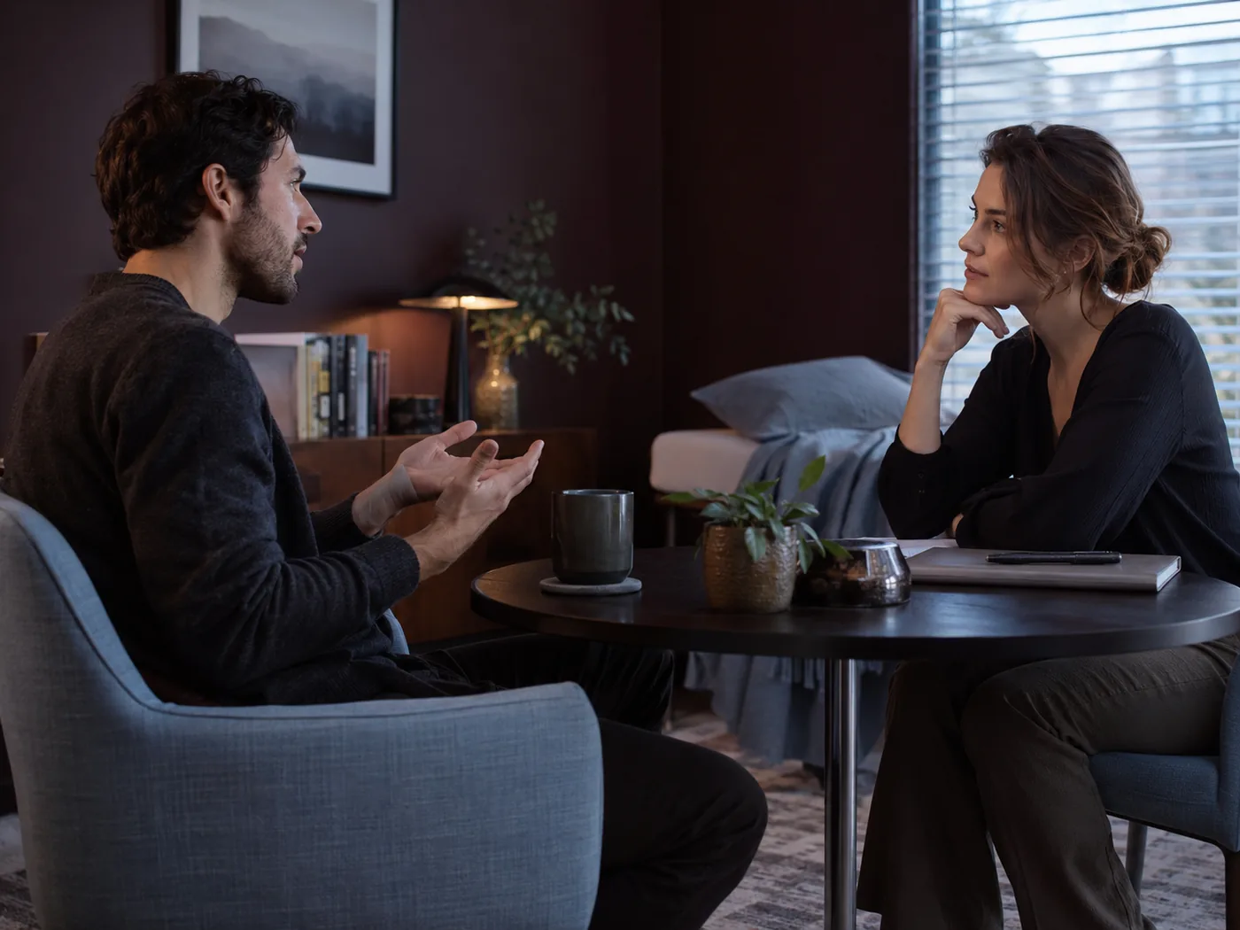 Two adults talking across a small table in a softly lit consultation room