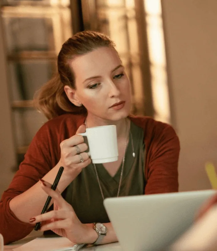 Founder taking a coffee break while reviewing work on a laptop