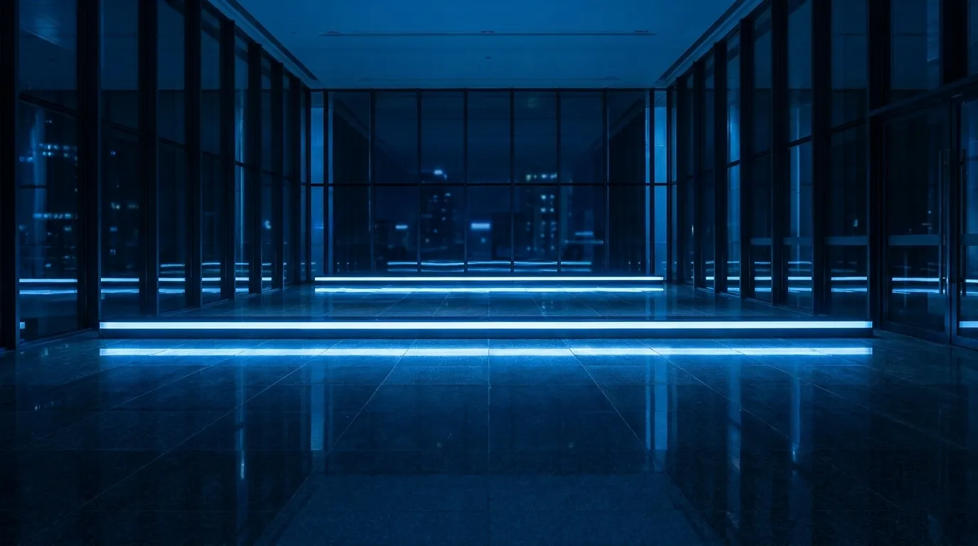 Blue-lit glass lobby at night — illustrative