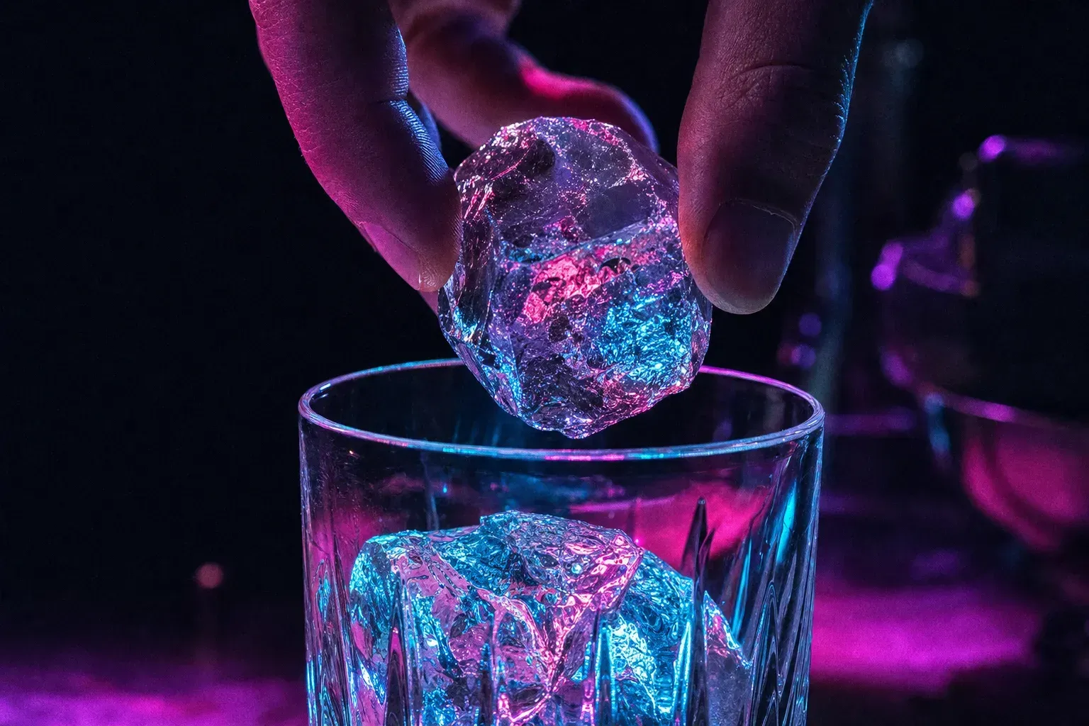 A hand-cut clear ice cube refracting the bar light