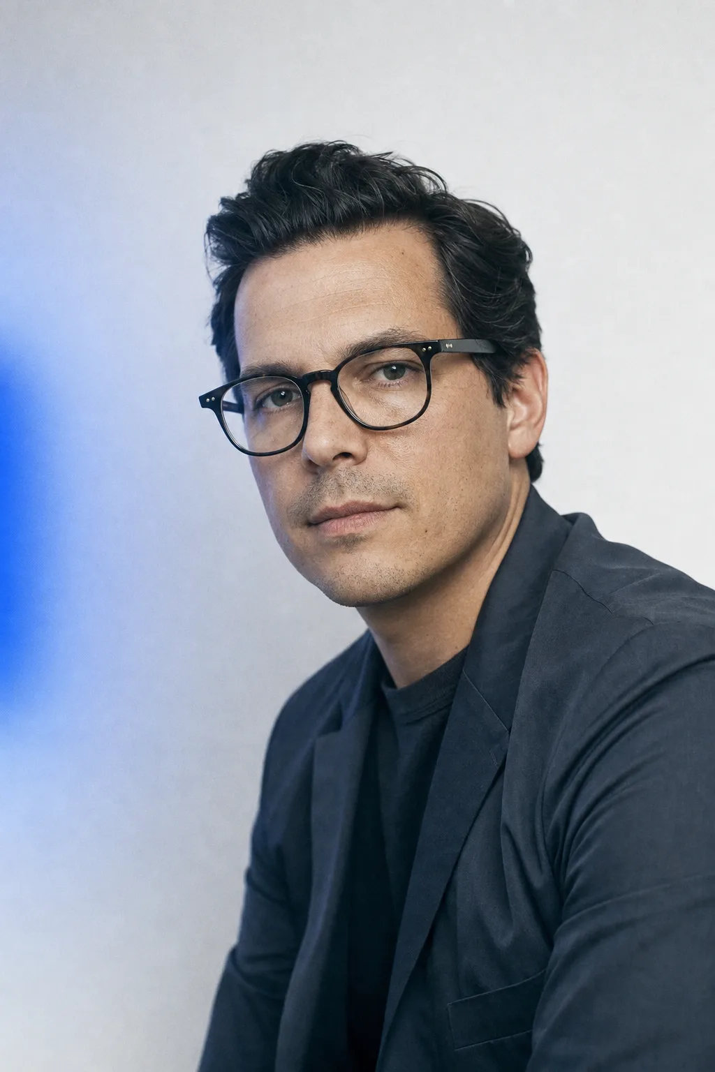Portrait of a man against a warm plain backdrop, unhurried expression.