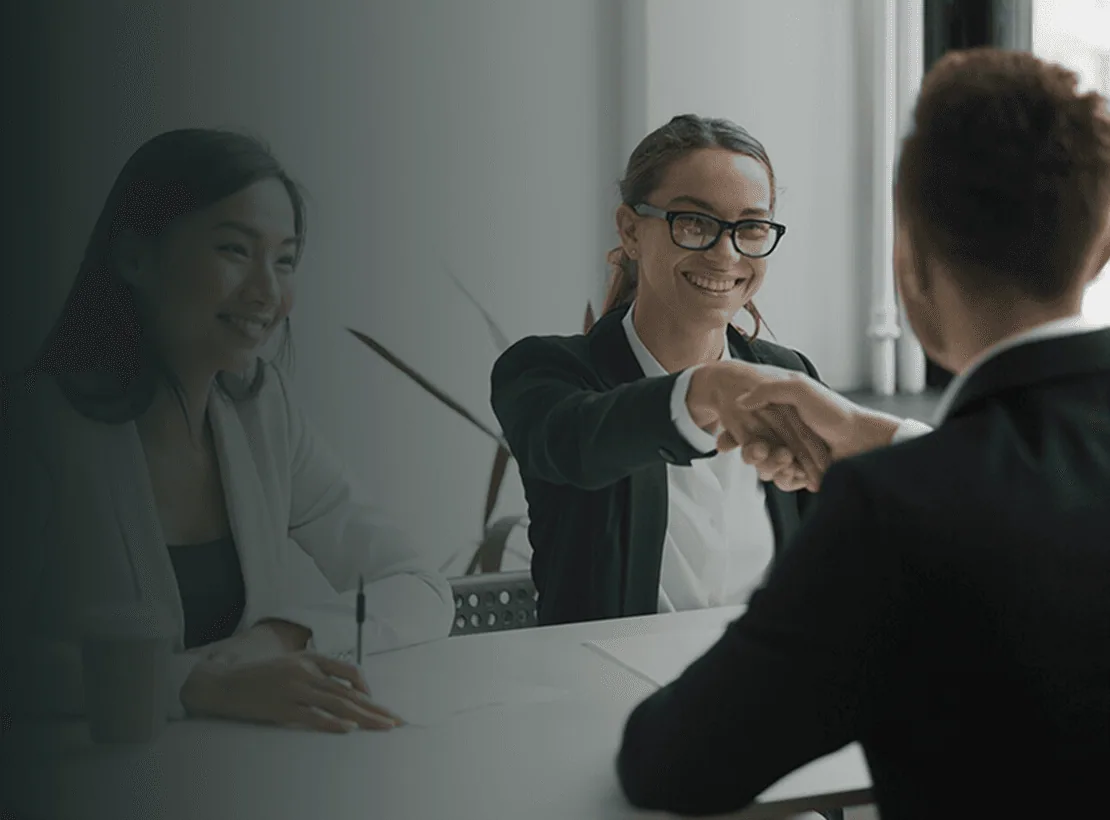 Two professionals shaking hands across a desk